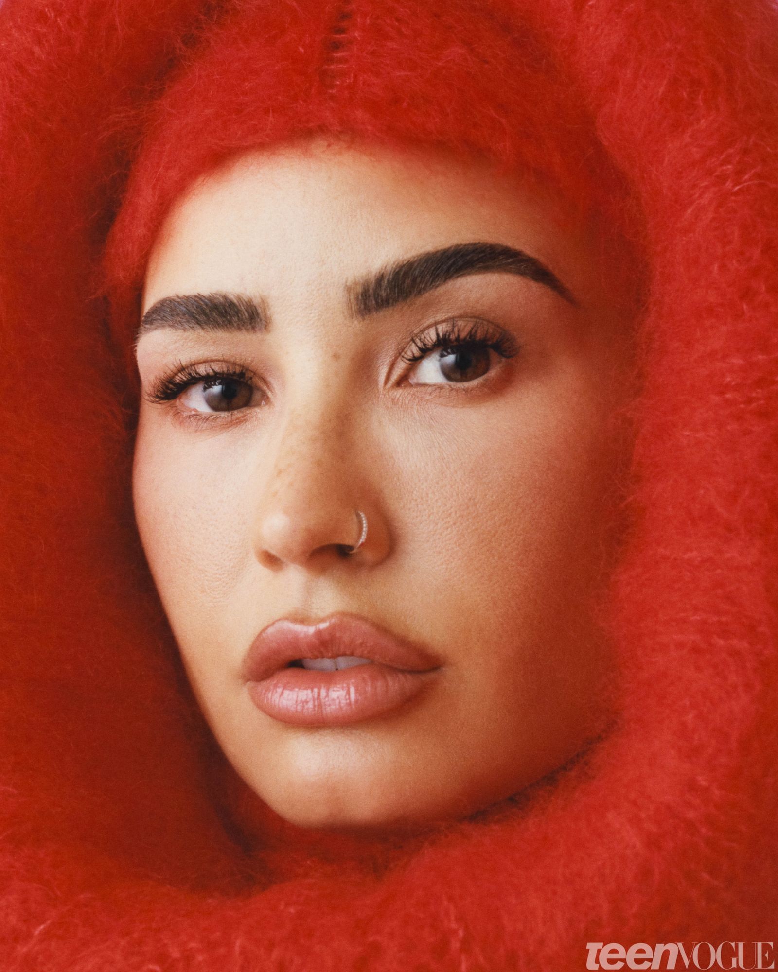 Tight portrait of Demi wrapped in a bright red fuzzy coat and hood.