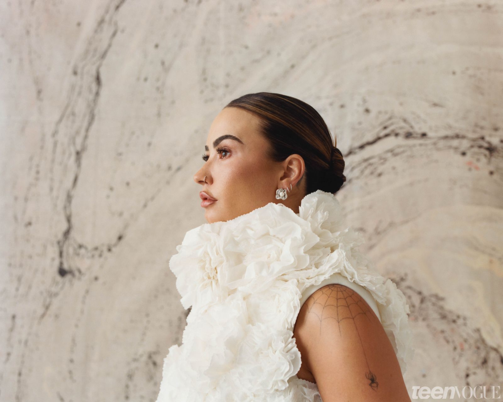Demi gazing to the left of frame in cream flowery dress.