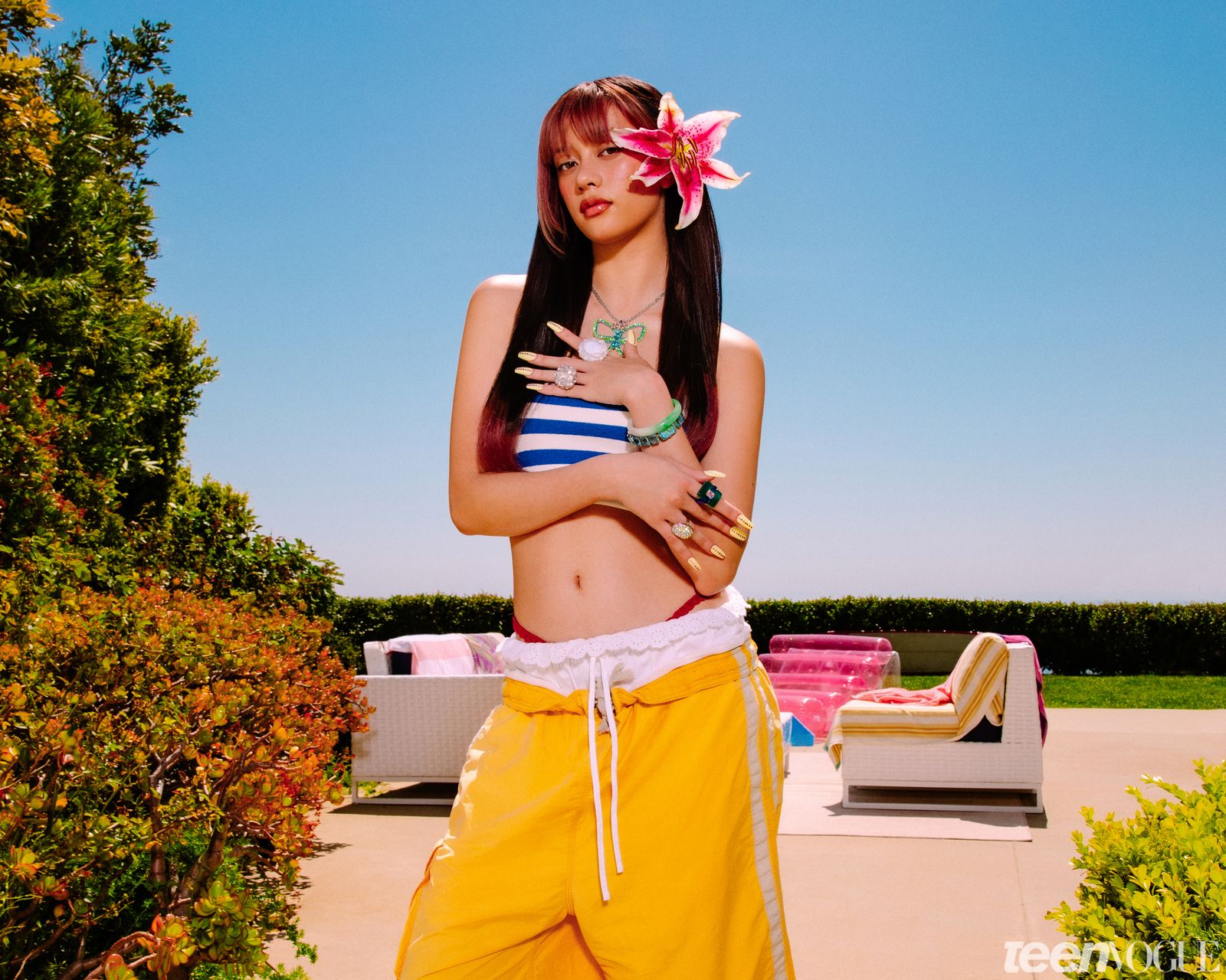 Megan photographed with a flower in her hair in a blue and white striped tube top.