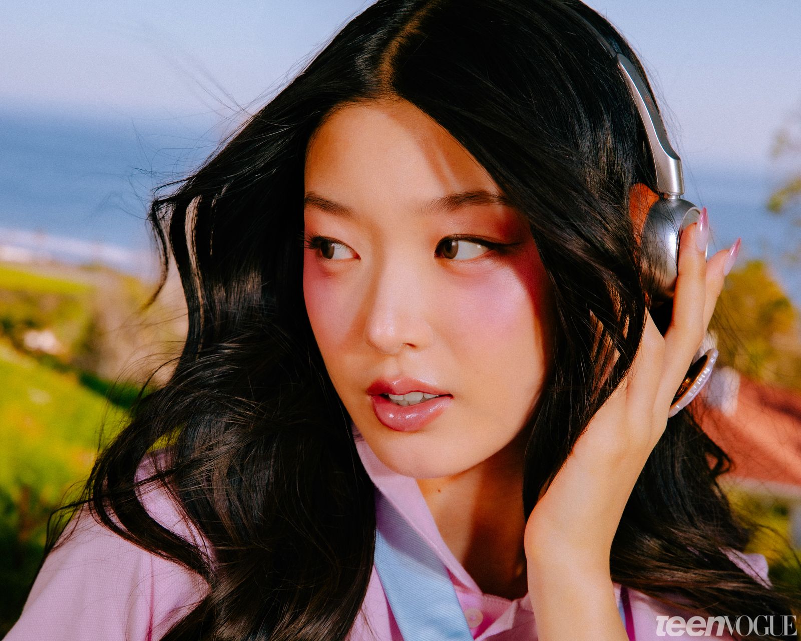 Yoonchae looking away from viewer photographed in the backyard listening to music with retro headphones.