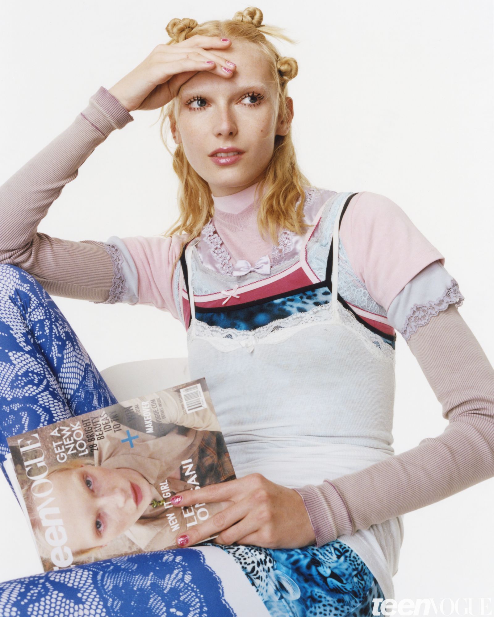 Alex looks away from viewer one hand is rested on her head and the other holding a mock Teen Vogue cover on her lap. The...