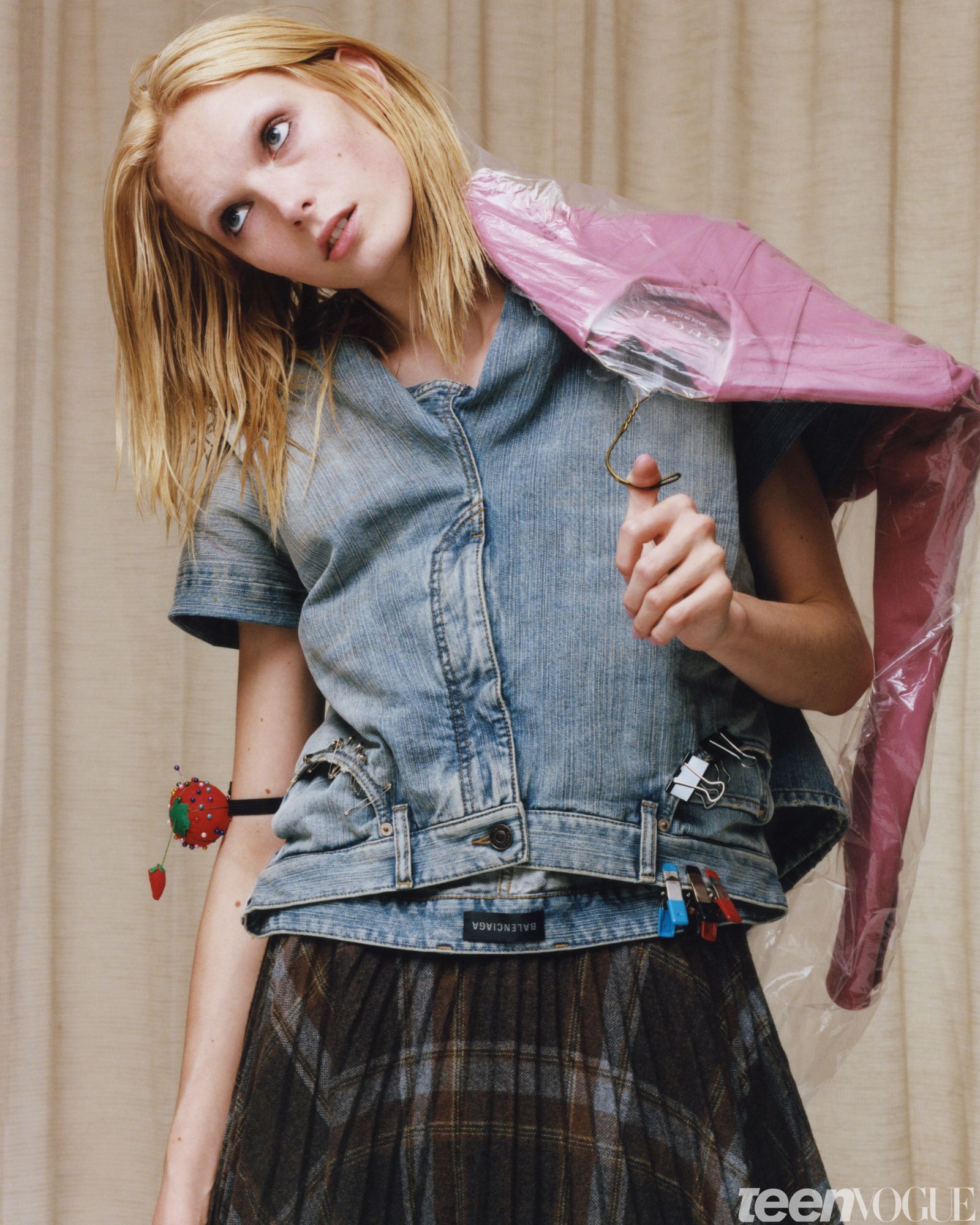 Alex as the Stylist. Alex rolls her eyes to the left frame while carrying a dry cleaning bag of a steamed pink jacket...