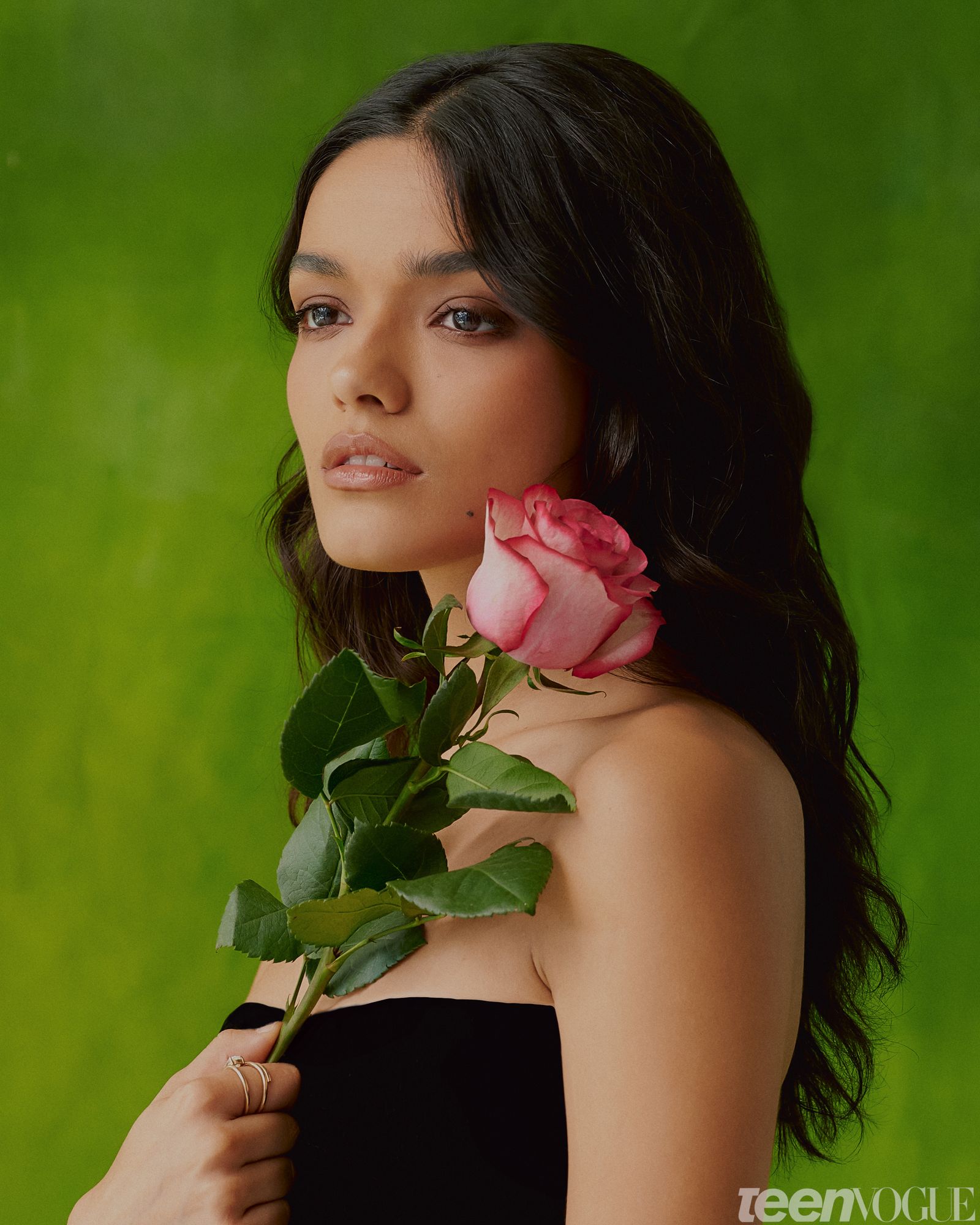 Closeup portrait of Rachel holding a pink rose wearing a strapless black gown.